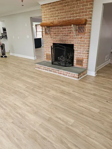 Clean open living room with brick fireplace and spotless light wood floors